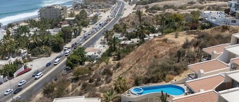Zona residencial costera con una carretera, piscina y edificios con tejas rojas.