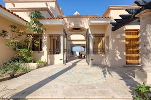 A courtyard with a tiled floor, a wooden door, and a view of the interior.