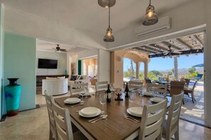 A dining area with a wooden table set for four, white chairs, and a view of the outdoors.
