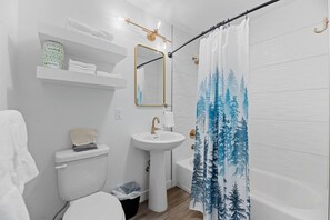 A bathroom with a toilet, sink, and shower curtain. - Queen City Inn and Extended Stay #5 (Spearfish)