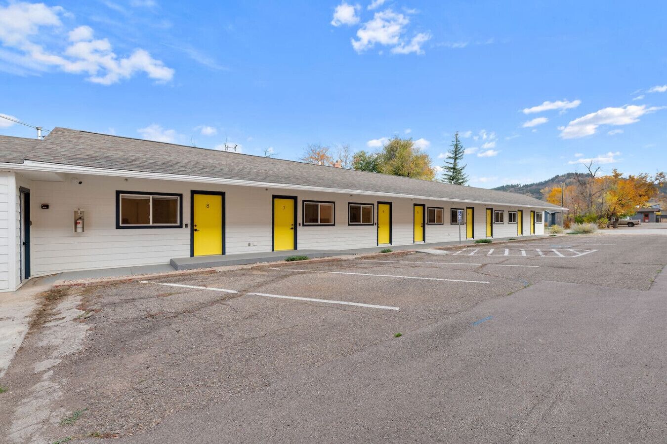 Ein Motel mit mehreren Zimmern, jedes mit einer gelben Tür, einem kleinen Fenster und einem Klingel.