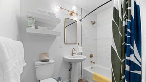 Un baño moderno con inodoro, lavamanos, ducha y toallero.