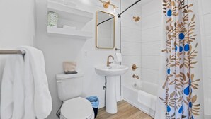 A modern bathroom with a toilet, sink, and bathtub. - Queen City Inn and Extended Stay #1 (Spearfish)
