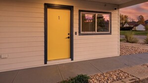 A single-story building with a yellow door and a window. - Queen City Inn and Extended Stay #1 (Spearfish)