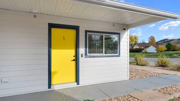 A single-story house with a yellow door, a window, and a covered porch.
