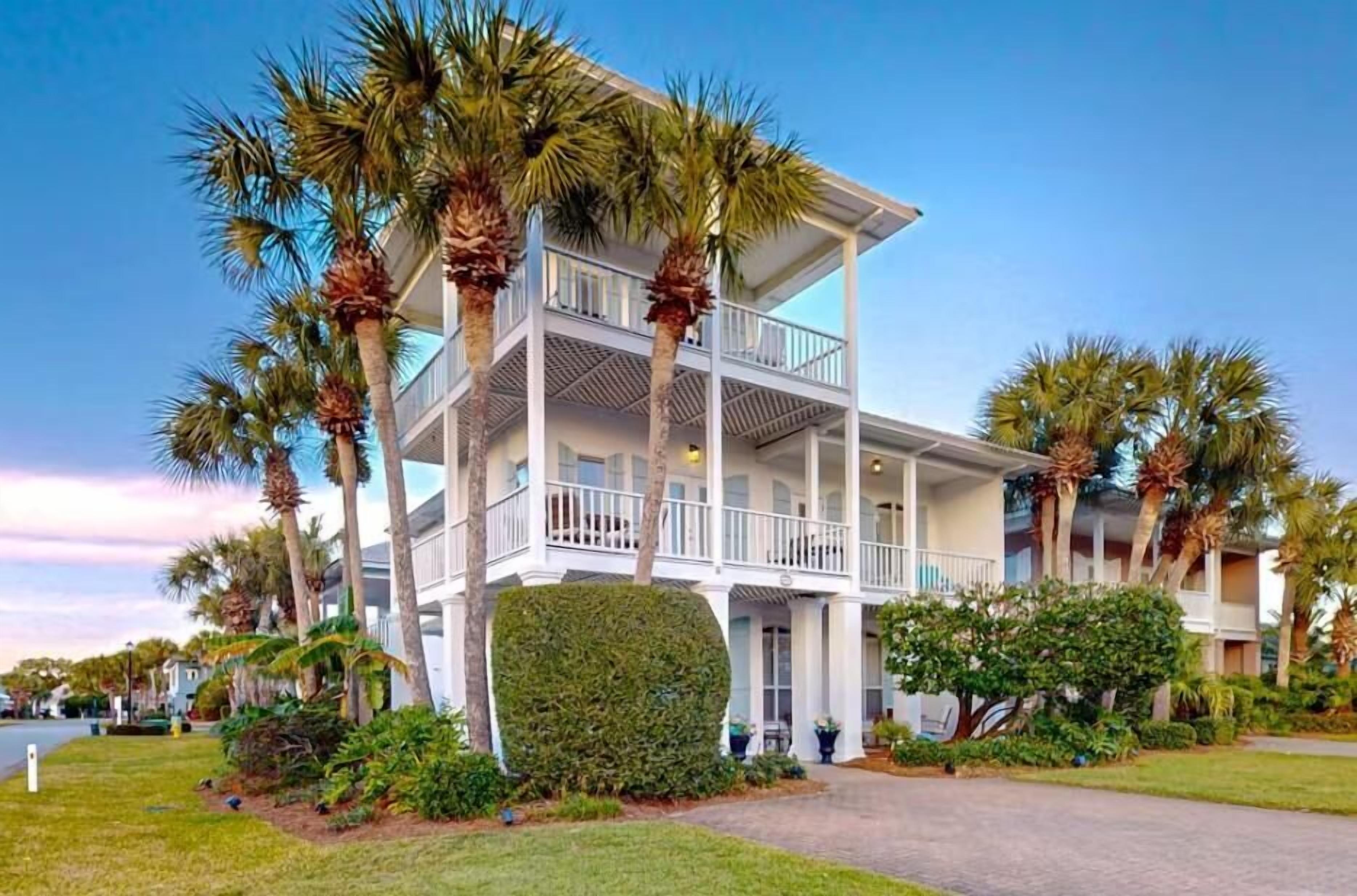 A multi-story hotel with balconies, surrounded by palm trees and well-maintained lawns.