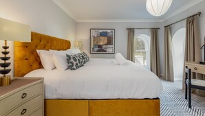 A neatly arranged bedroom with a large bed, bedside tables, a desk, and a window with curtains. - Skye Sands | St Mary’s Gardens (No 7) (St Andrews)
