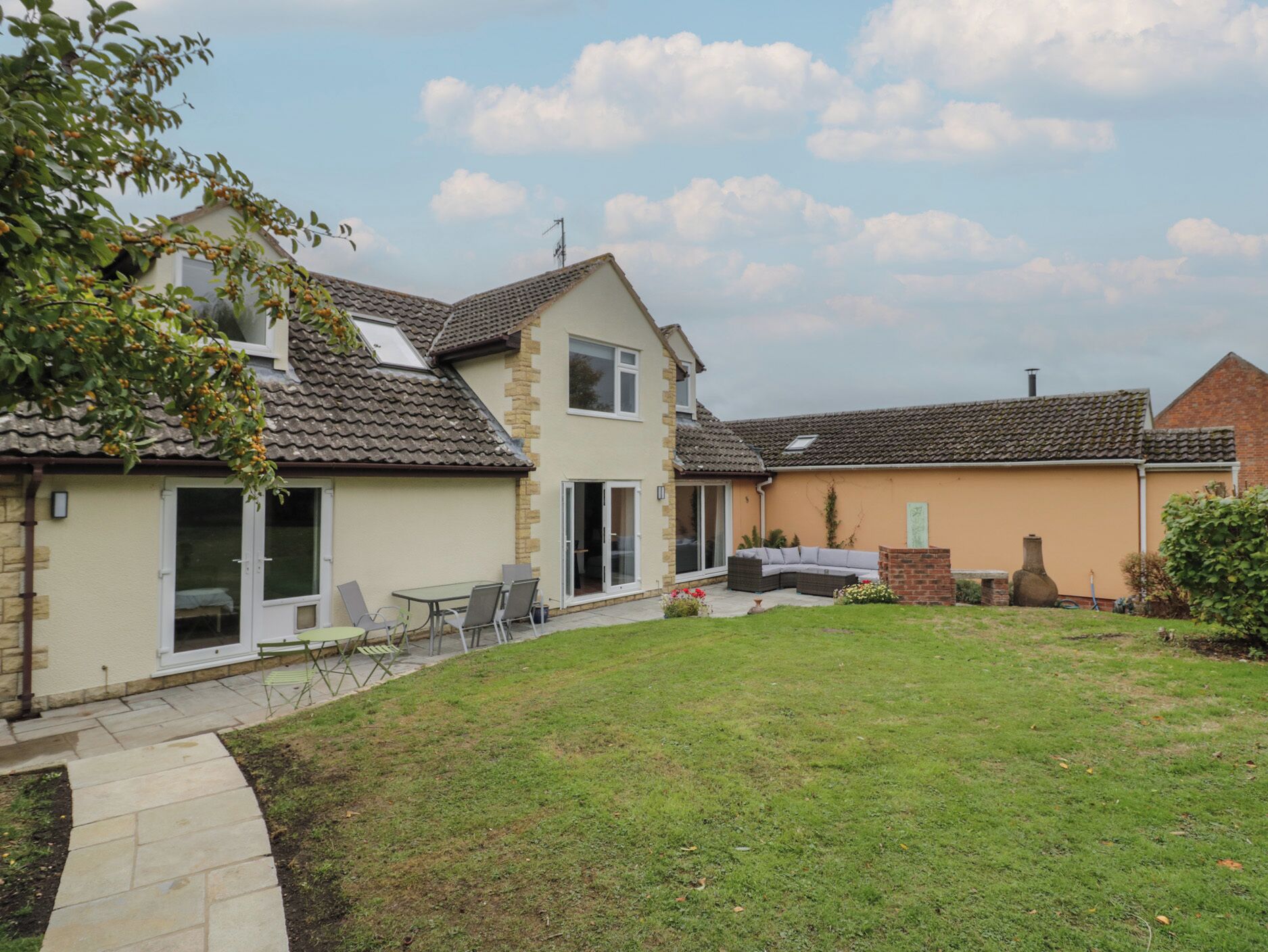 A two-story house with a patio, a lawn, and a brick chimney.