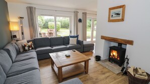 A cozy living room with a sofa, a coffee table, and a fireplace. - Harran (Pershore)