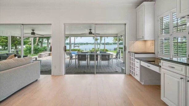 A modern interior with a dining area, kitchen, and a view of a body of water.