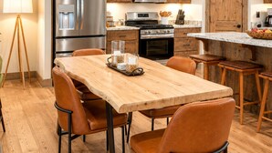 Een moderne keuken met roestvrijstalen apparatuur, een houten eettafel en bruine leren stoelen.