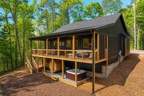 Una baita con veranda in legno, vasca idromassaggio e fondamenta in pietra.