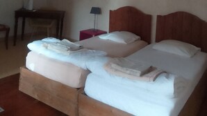 Una habitación con dos camas, un escritorio, una silla y una lámpara.