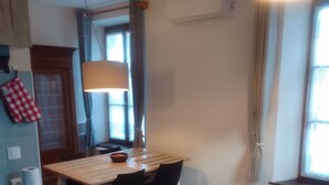 Una cocina compacta con zona de comedor, una ventana con cortinas y un suelo estampado.
