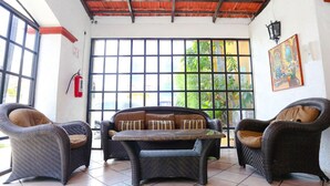 A room with wicker furniture, a tiled floor, and a large window with a view of greenery. - 4 Units | City & Beach Getaway | Poolside Stay Near Hotel Zone & Local Markets (Cancún)