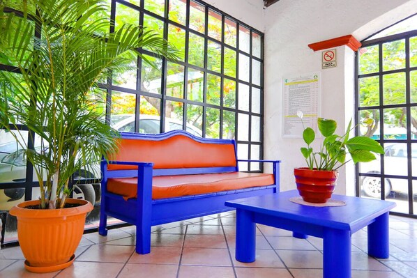 Une pièce avec un banc bleu, un banc rouge et une plante en pot.