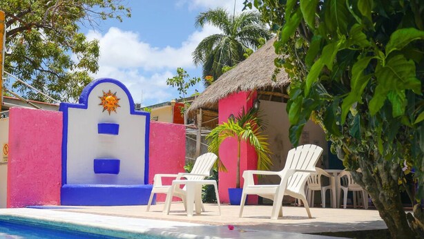 A swimming pool with white lounge chairs and a thatched-roof building in the background. - 4 Units | City & Beach Getaway | Poolside Stay Near Hotel Zone & Local Markets (Cancún)