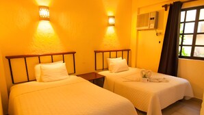 A hotel room with two beds, each with a pillow and a nightstand. There are wall-mounted lights above the beds and a window with curtains. - 4 Units | City & Beach Getaway | Poolside Stay Near Hotel Zone & Local Markets (Cancún)