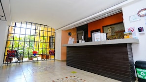 A reception area with a counter, chairs, and a view through large windows. - 4 Units | City & Beach Getaway | Poolside Stay Near Hotel Zone & Local Markets (Cancún)