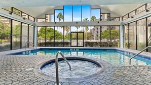 A pool area with a hot tub, clear glass walls, and a view of palm trees and buildings. - Modern 2-Bedroom Enclave Condo Retreat (Orlando)