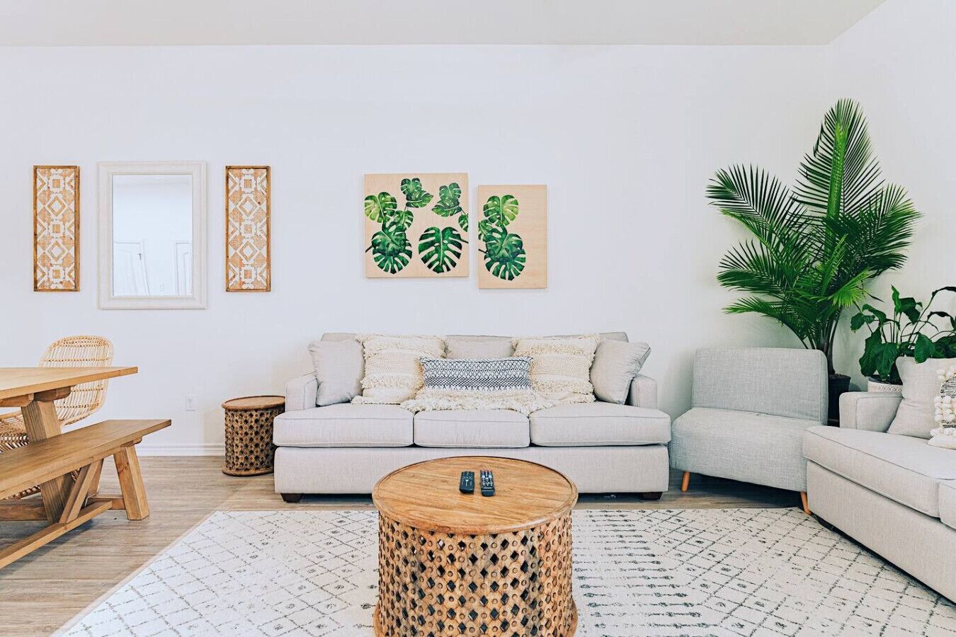 Ein Wohnzimmer mit einem hellen Sofa, einem Holztisch und einem gemusterten Teppich.