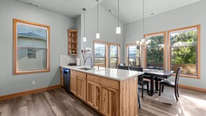A modern kitchen with wooden cabinets, a central island, and pendant lighting.