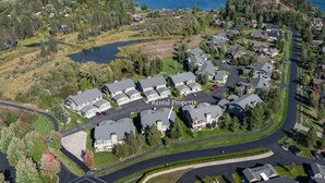 An aerial view of a residential area with houses, a lake, and a mountain range in the background.
