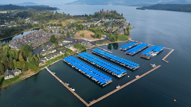 An aerial view of a residential area with a marina, rental properties, and a large body of water.