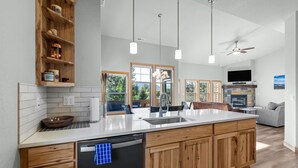 A modern kitchen with a large island, wooden cabinets, and a built-in dishwasher.