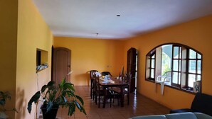 A dining area with a table and chairs, a potted plant, and a large window with a view. - Charming place, with a cozy single-story house. (Mairinque)