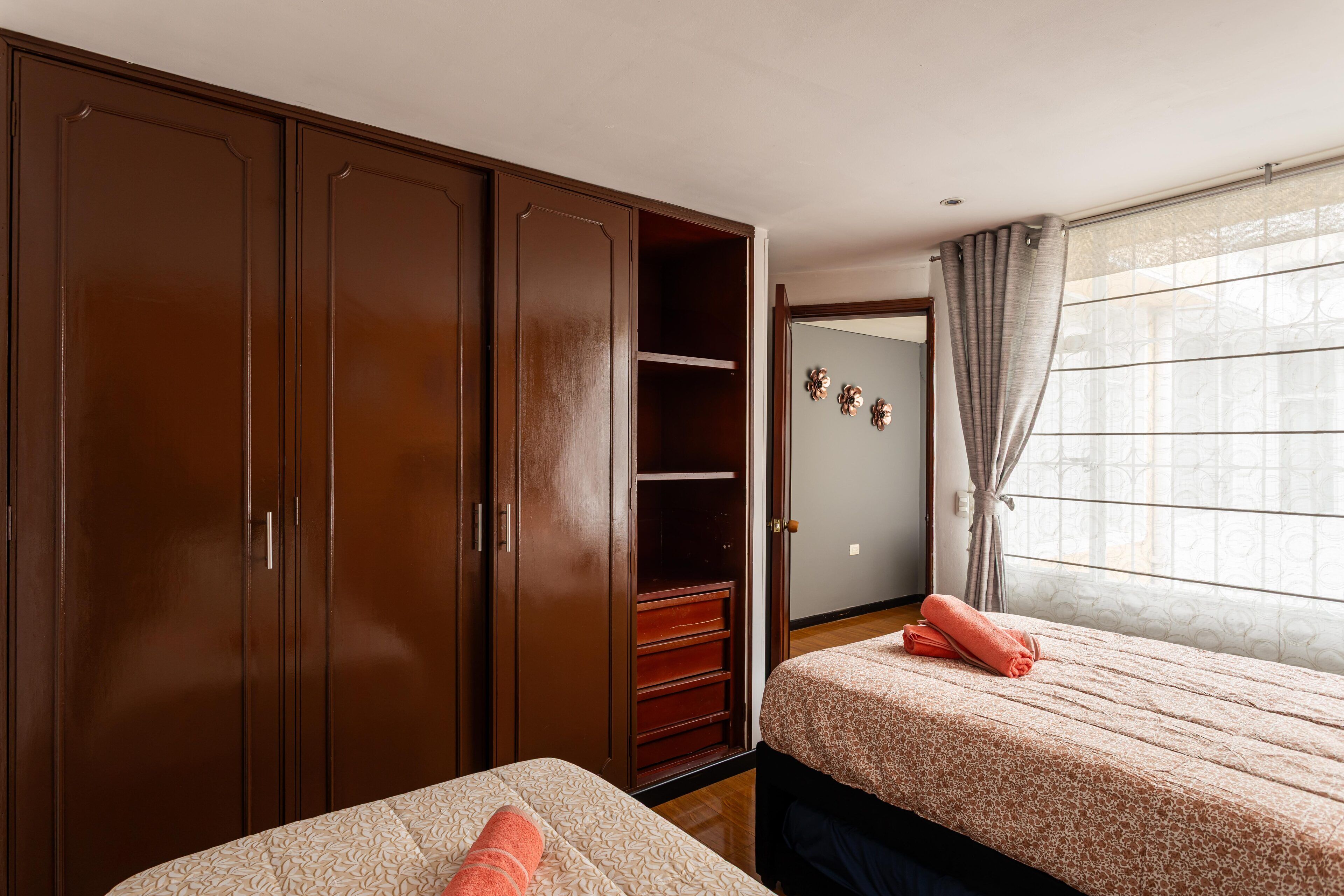 Een slaapkamer met twee bedden, een kledingkast en een raam met gordijnen.