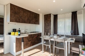A modern kitchen with a central island, dining table, and chairs.