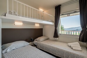 A bedroom with two beds, a window with a view, and a balcony.