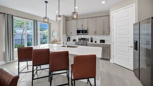 A modern kitchen with a central island, stainless steel appliances, and pendant lighting. - Inviting Townhome near Disney with Resort & Waterpark Access - 7833SD (Kissimmee)