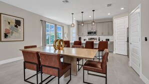 A modern kitchen with white cabinets, a central island, and pendant lighting. - Inviting Townhome near Disney with Resort & Waterpark Access - 7833SD (Kissimmee)