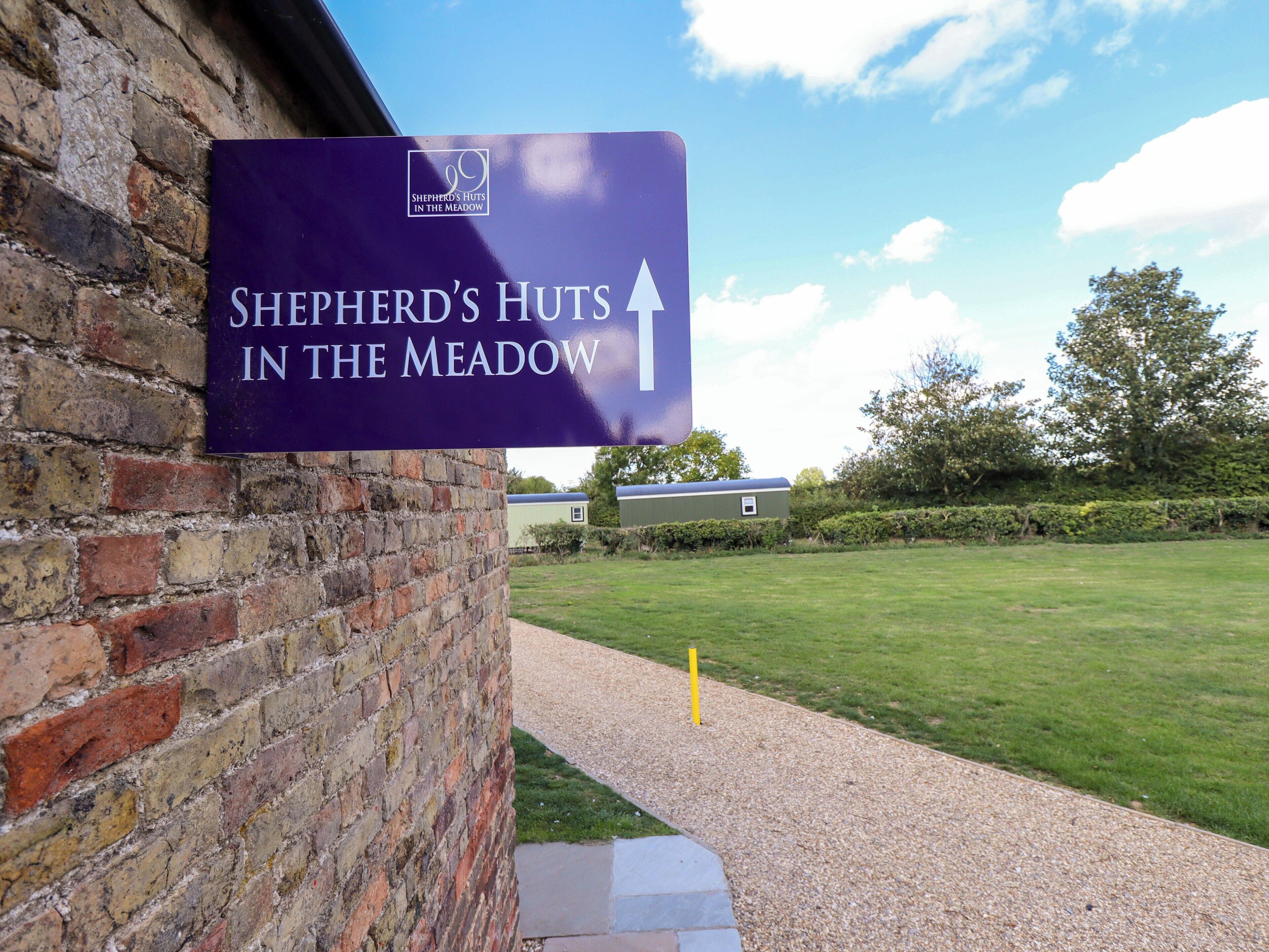 A sign for Shepherd's Huts in the Meadow, indicating the direction to the property.