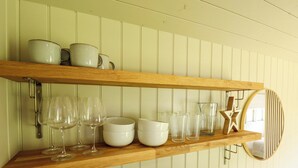 Una repisa de cocina con vajilla blanca, vasos y un adorno de estrella de madera.