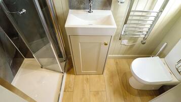 Un baño con cabina de ducha de vidrio, un lavamanos blanco y un inodoro.