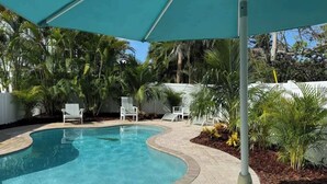A swimming pool with a curved edge, surrounded by a brick patio and white lounge chairs. - Mermaid’s Purse~Private Pool! 40 steps to beach! (Anna Maria)