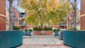 A courtyard with brick buildings, a central planter with greenery, and outdoor seating.