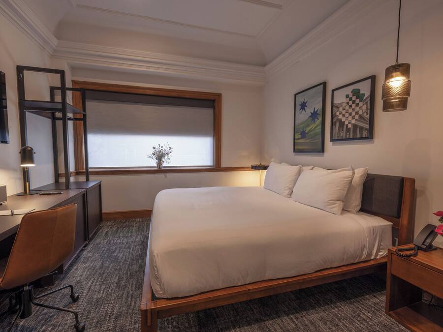 Un dormitorio con cama, escritorio, silla y ventana con vistas.