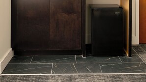 A kitchen with a dark wooden cabinet, a black refrigerator, a tiled backsplash, and a shelf with glasses and a framed picture. - The Promissory Hotel (Roanoke)