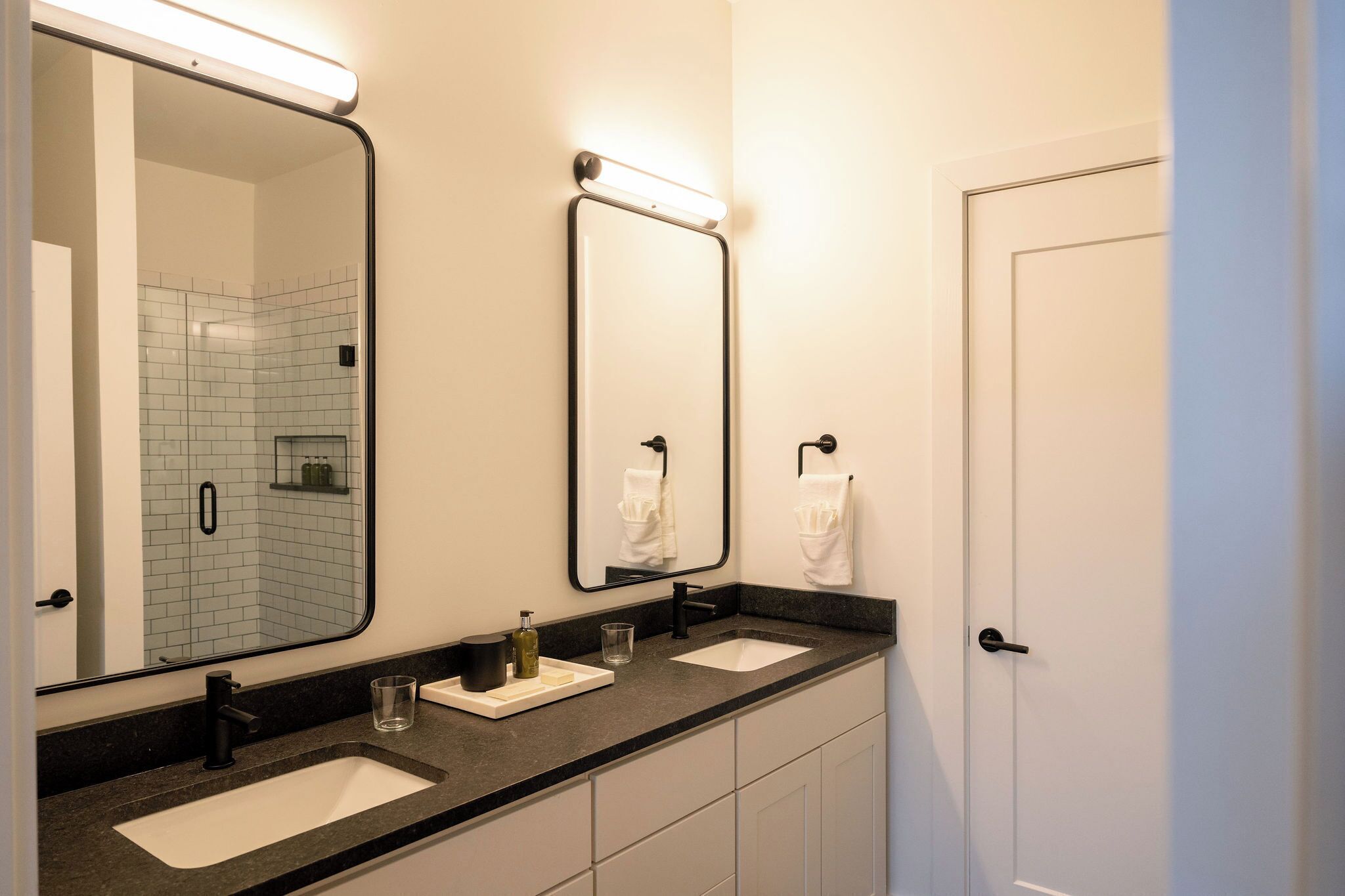 A bathroom with two sinks, a large mirror, and a towel rack.