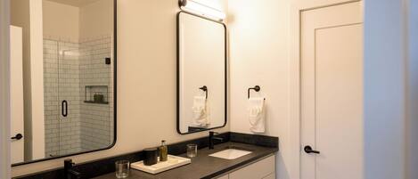 A bathroom with two sinks, a large mirror, and a towel rack.