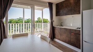 A modern kitchen with a balcony, white countertops, and dark cabinets. - Mobile Home 'Camping Belsito Evo Medium 511' with Shared Pool, Wi-Fi & Air Conditioning (Vico)
