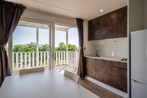 A modern kitchen with a balcony, white countertops, and dark cabinets.