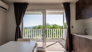 A room with a sliding glass door leading to a balcony with a view of greenery and mountains. - Mobile Home 'Camping Belsito Evo Medium 511' with Shared Pool, Wi-Fi & Air Conditioning (Vico)