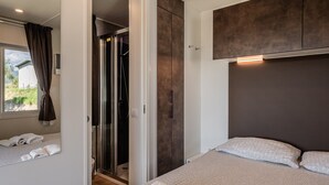 A bedroom with a bed, a walk-in closet, and a shower area. - Mobile Home 'Camping Belsito Evo Medium 511' with Shared Pool, Wi-Fi & Air Conditioning (Vico)
