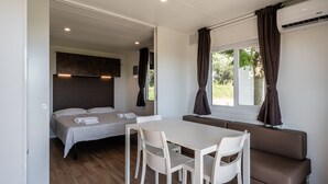A compact room with a bed, a dining table, and a sofa. - Mobile Home 'Camping Belsito Evo Medium 511' with Shared Pool, Wi-Fi & Air Conditioning (Vico)