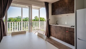 Une cuisine moderne avec un balcon, des plans de travail blancs et des meubles de rangement sombres.